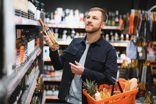 Mężczyzna wybiera wino w supermarkecie