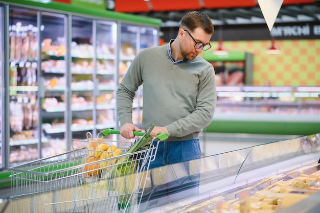 Mężczyzna wybierający ser w supermarkecie