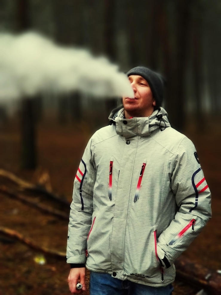 Zdjęcie mężczyzna wydychający dym stojący w lesie