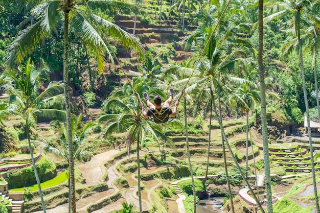 Mężczyzna wymachuje huśtawką w dżungli na wyspie z tarasami ryżowymi Bali Ubud Indonezja