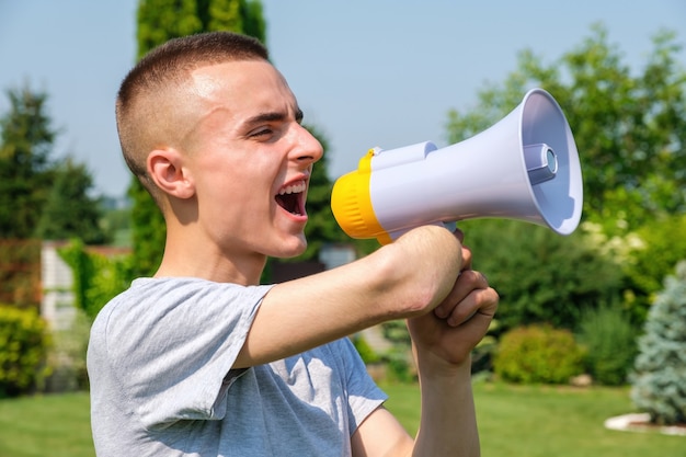 Mężczyzna z amputowaną ręką i protezą krzyczy do megafonu na zewnątrz