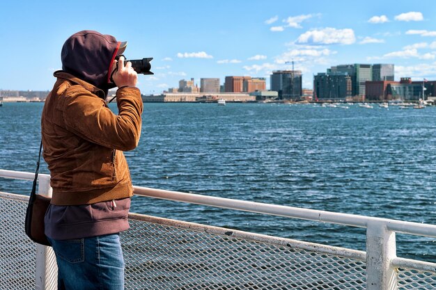 Mężczyzna z aparatem nad rzeką Charles z panoramą miasta w tle w Bostonie, Ameryka