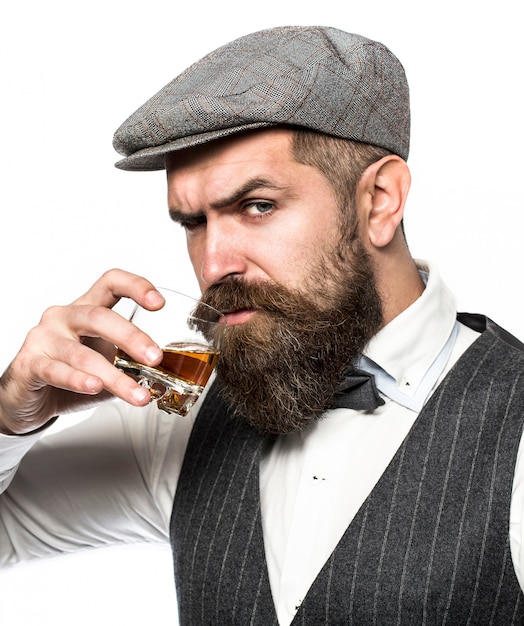 Mężczyzna z brodą trzyma szklaną brandy. Brodaty drink koniak.
