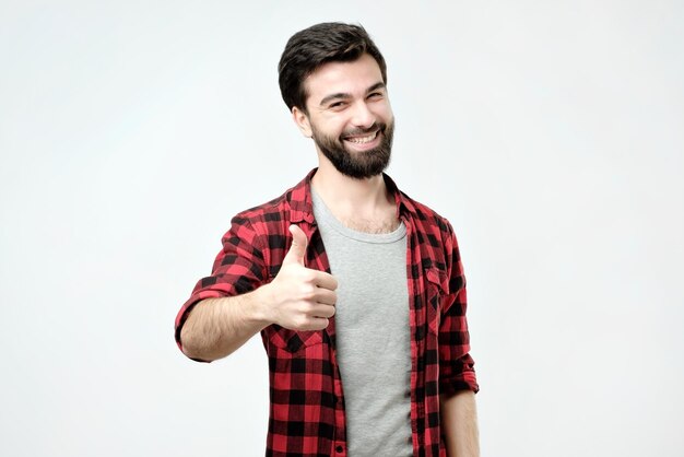 Mężczyzna z brodą unoszący kciuki do góry i szeroko uśmiechający się, dający pozytywne opinie