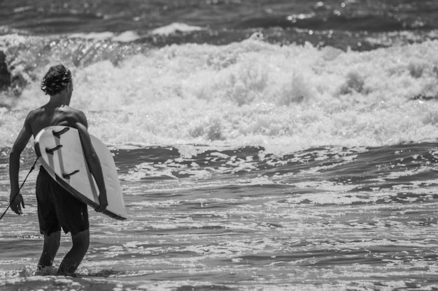 Mężczyzna z deską do surfowania w morzu