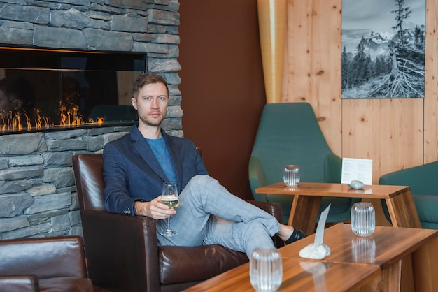 Mężczyzna z kieliszkiem do wina siedzi na krześle w luksusowym hotelu podczas wakacji