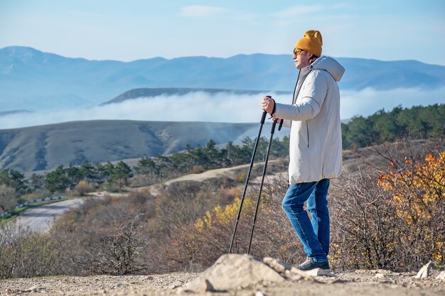 Zdjęcie mężczyzna z kijami do nordic walking stoi wysoko w górach i patrzy przed siebie
