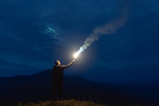 Mężczyzna z kijem fajerwerków stojący na górze. pora nocna