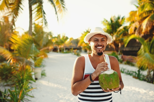 Mężczyzna z kokosem na tropikalnej plaży w słoneczny letni dzień podczas wakacji