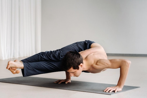 Mężczyzna z kościstym torsem trenuje w pozycji leżącej, stając na rękach na siłowni