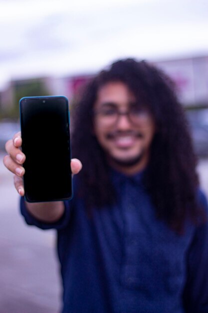 Zdjęcie mężczyzna z kręconymi długimi włosami trzyma telefon