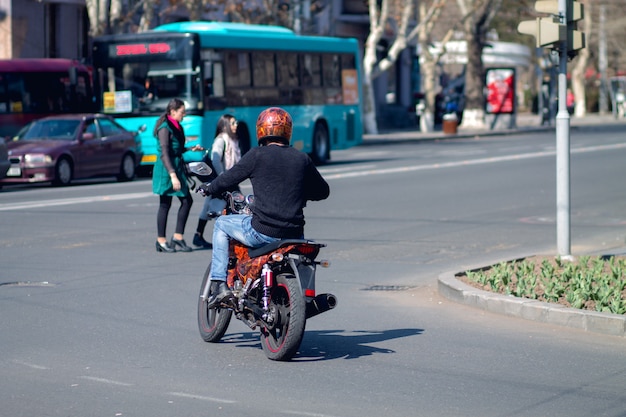 Mężczyzna z motocyklem jadący przez skrzyżowanie