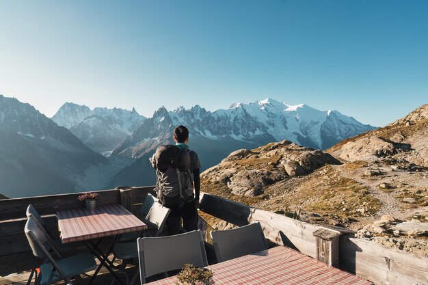 Mężczyzna z plecakiem cieszy się widokiem na masyw Mont Blanc na balkonie w Alpach francuskich we Francji