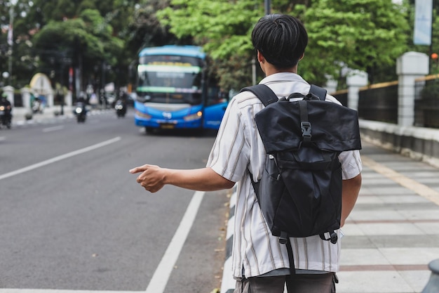 mężczyzna z plecakiem czekający na autobus turystyczny do spacerów po mieście po stronie drogi