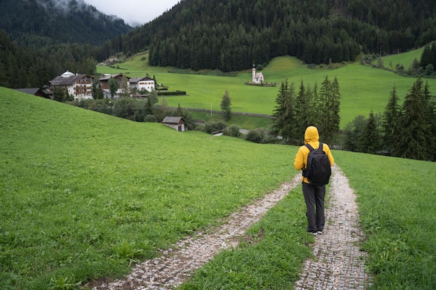 Mężczyzna z plecakiem wędrujący w dół doliny Val di Funes do kościoła St Johann Dolomity Włochy Europa