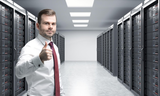 Mężczyzna z prawym kciukiem w serwerowni do przetwarzania i analizy przechowywania danych dwa rzędy maszyn w pracy