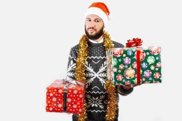 Mężczyzna z prezentem świątecznym w rękach w Studio na białym tle wybiera prezent