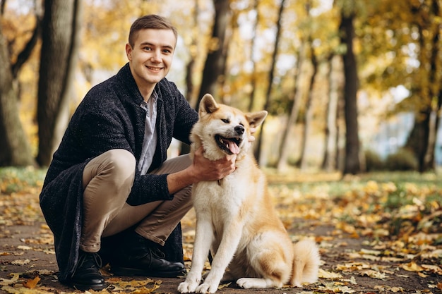 Mężczyzna z psem spacerujący po jesiennym parku