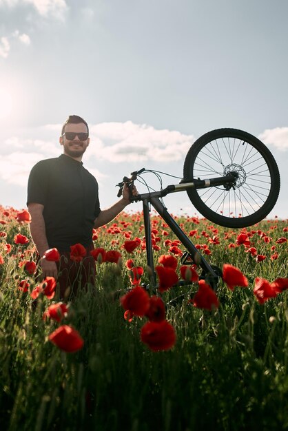 Mężczyzna z rowerem w czerwonym polu maku Koncepcja przygód na świeżym powietrzu podczas letnich wakacji i weekendów