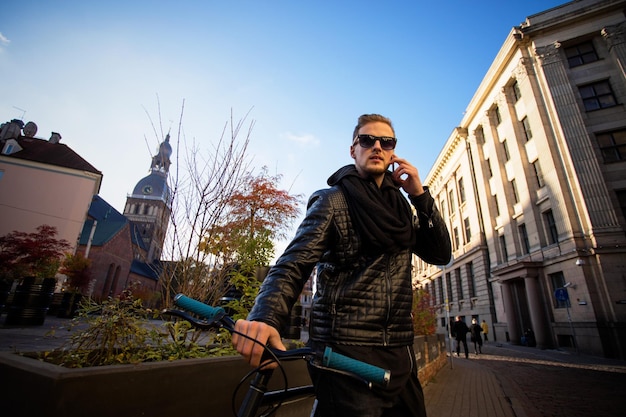 Zdjęcie mężczyzna z rowerem w mieście rozmawia przez telefon