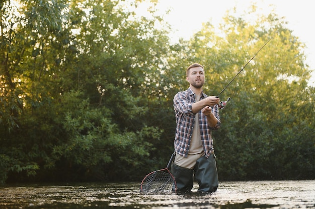 Mężczyzna z wędką rybak mężczyźni w wodzie rzeki na zewnątrz Łowienie pstrągów w sieci Letnie hobby wędkarskie