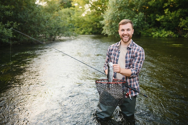 Mężczyzna z wędką rybak mężczyźni w wodzie rzeki na zewnątrz Łowienie pstrągów w sieci Letnie hobby wędkarskie