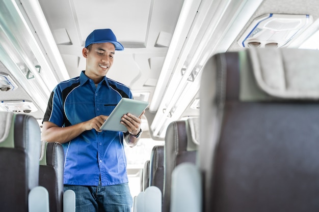 Mężczyzna z załogi autobusu korzystający z cyfrowego tabletu, stojąc w autobusie
