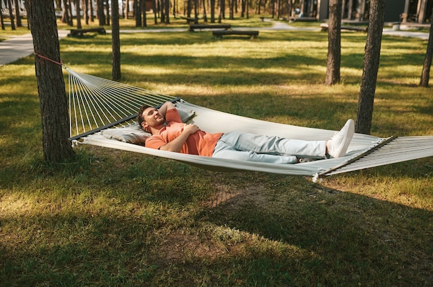 Mężczyzna z zamkniętymi oczami leżący w hamaku w naturze