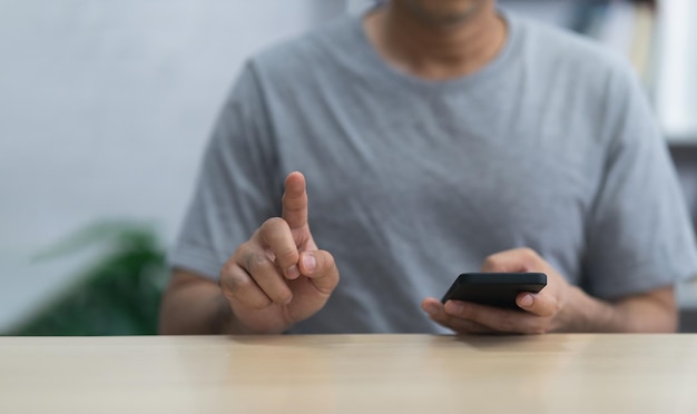 Mężczyzna za pomocą smartfona i ekranu dotykowego palcem wskazującym, siedząc na stole Koncepcja technologii biznesowej metaverse technologia inteligentnego telefonu