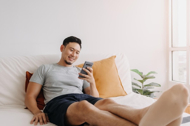 Mężczyzna zadowolony z aplikacji mobilnej podczas relaksu na kanapie