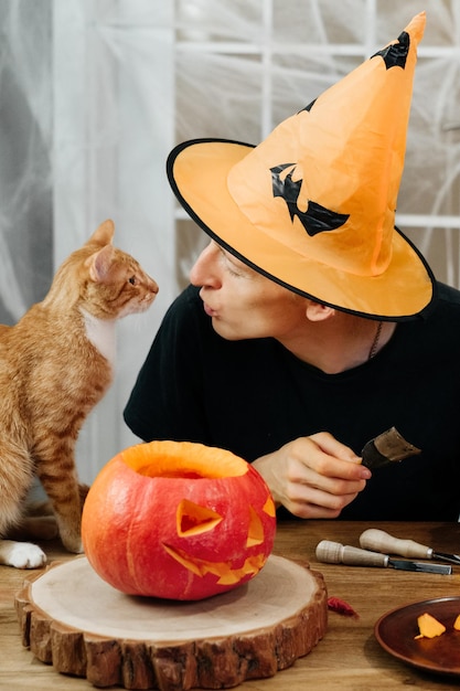 Zdjęcie mężczyzna zakrzywiony jac o lanten halloween dyni w domu przygotowuje się na święta