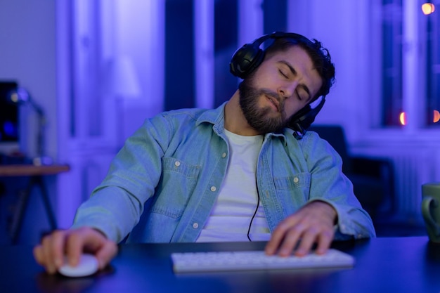 Mężczyzna zasnął grając na komputerze w pomieszczeniu oświetlonym neonem.