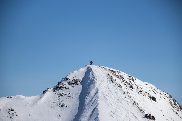 Mężczyzna ze snowboardem na szczycie zaśnieżonej kaukaskiej góry