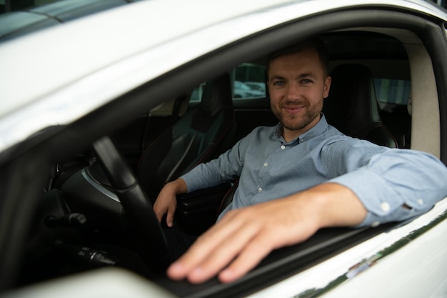 Mężczyzna ze stylem i statusem Przystojny młody mężczyzna w pełnym garniturze uśmiechający się podczas prowadzenia samochodu