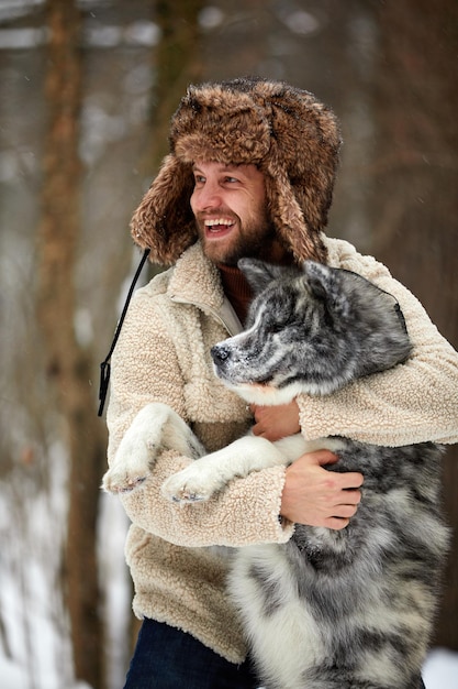 Mężczyźni bawiący się z siberian husky w zimowych zwierzętach leśnych i parkowych oraz ekologia Miłośnik zwierząt domowych Koncepcja przyjaciela psa człowieka