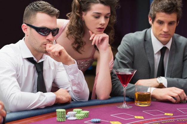 Mężczyźni i kobiety siedzą przy stole do pokera