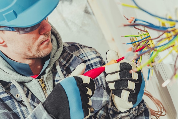 Mężczyźni instalujący rząd gniazdek elektrycznych w nowo wybudowanym domu