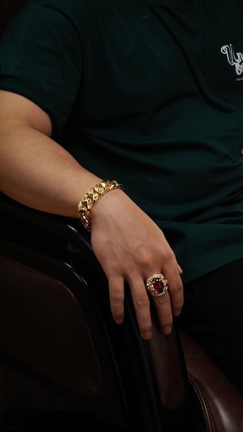 mężczyźni noszący na ręce złotą bransoletkę i złote pierścionki