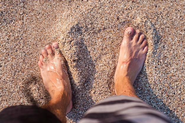 Mężczyźni stoją boso na piaszczystej plaży.