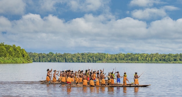 Mężczyźni z plemienia Asmatów pływają w kajaku po rzece. Amanamkay. Wioska, prowincja Asmat, Indonezja