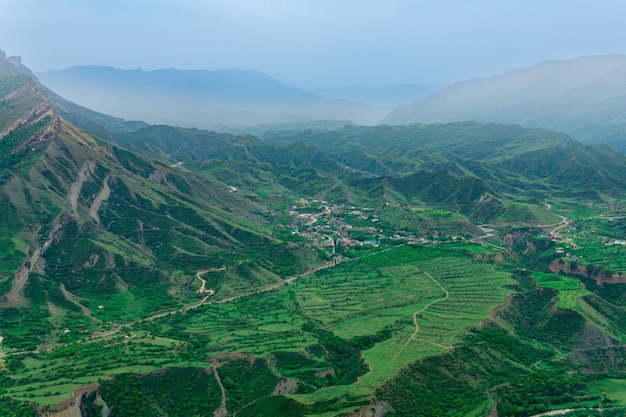 Mglista dolina wyżynna z krajobrazami i polami między górskimi szczytami