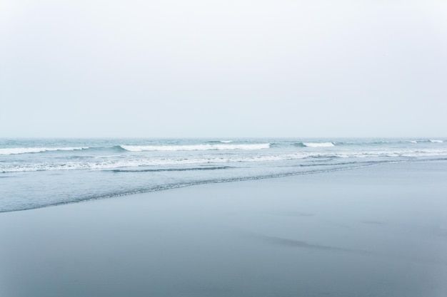 Mglisty pejzaż morski zimny brzeg oceanu z szeroką plażą