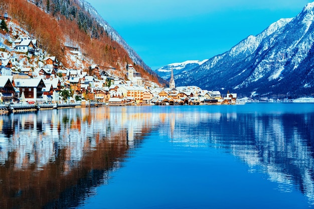 Miasto Hallstatt w Salzburgu w Austrii, Europie. Zima w Salzkammergut. Podróż do austriackiego miasta z jeziorem na Boże Narodzenie. Teren alpejski ze śniegiem. Widok na wioskę w pobliżu Alp z pięknym kościołem?