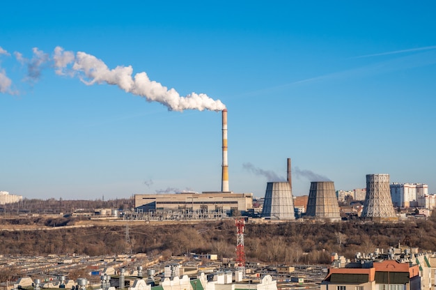 Miasto zimą, biały dym z rury elektrowni unosi się między domami