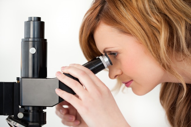 Zdjęcie miedzianowłosy naukowiec patrzeje przez mikroskopu