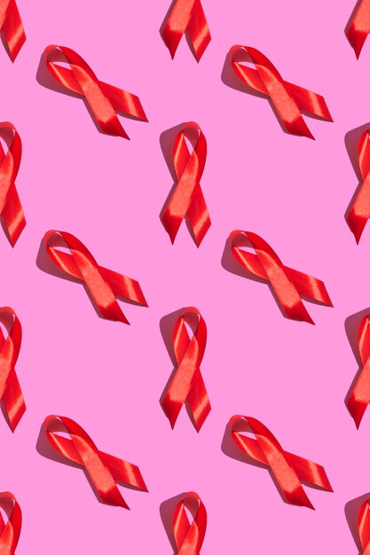 Międzynarodowy Dzień AIDS. Czerwona wstążka z twardym cieniem na różowym tle. Koncepcja świadomości AIDS. Zdjęcie pionowe. Wzór