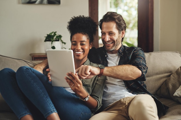 Międzyrasowa para tablet i szczęśliwy w domu do zakupów wybór i decyzja razem na kanapie Mężczyzna kobieta i technologia na kanapie dla pomysłów ślubnych burza mózgów i e-commerce w salonie na stronie internetowej
