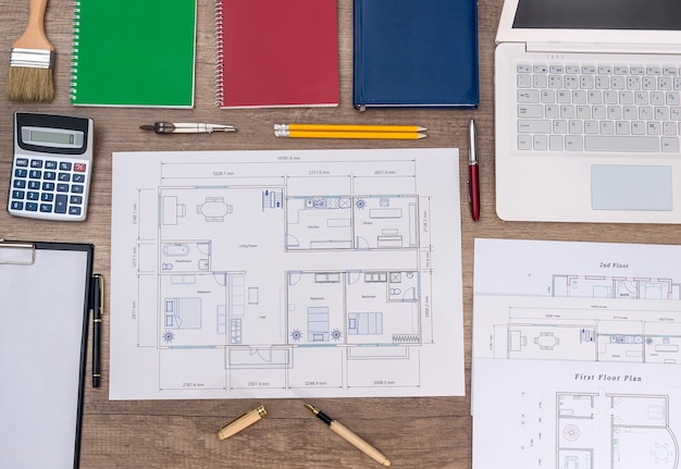 Miejsce pracy architekta z planem domu, laptopem i kalkulatorem
