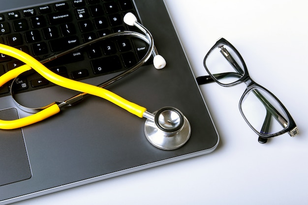 Zdjęcie miejsce pracy lekarka z laptopem, stetoskopem i rx receptą na bielu stole