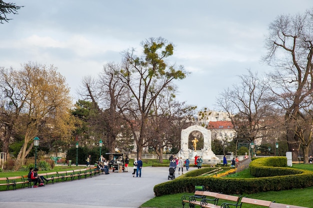 Zdjęcie miejscowi i turyści przy pomniku johanna straussa ii w stadtpark w zimny wczesny wiosenny dzień